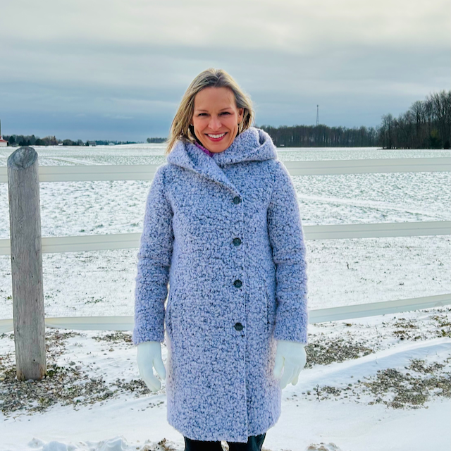Ginette Blake, wearing a light blue winter jacket, standing infront of a fence with a winter rural background.