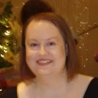 A photo of Tracy standing infront of a brown background, smiling. Shoulder length brown hair.